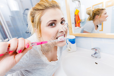 女人刷牙特写趣的金发女孩带着牙刷浴室口腔卫生寻常的广角视图女人浴室刷牙图片