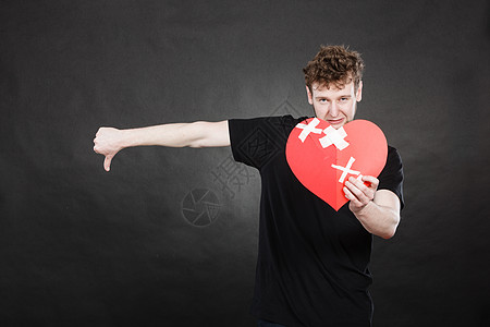 分手,悲伤情绪的非常悲伤的轻人抱着破碎的心,用纸,拇指向下的手势