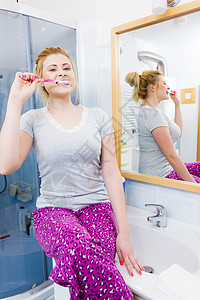 女人刷牙特写趣的金发女孩带着牙刷浴室口腔卫生女人浴室刷牙图片