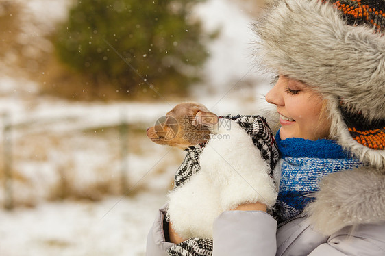轻的女人用温暖的毯子围巾把她最好的朋友小狗包裹来,寒冷的雪天里温暖他动物保护拯救收养女人拥抱温暖她的小狗图片