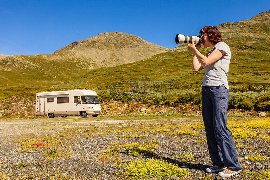 旅游度假旅游女游客用相机拍照背景中的露营车旅游路线极光露营车游客带相机山上图片