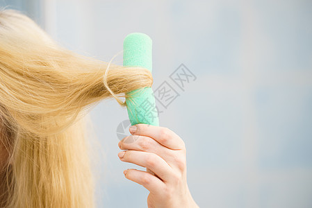 金发女人用卷发器她的发型上创造美丽的发型金发女人用卷发器图片
