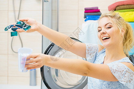 快乐趣的女人展示洗衣机洗衣舱,胶囊,洗涤剂粉末,家务化学品物体快乐的女人展示洗衣舱,胶囊粉末图片