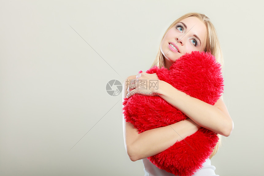 情人节爱情关系金发长发轻女子拥抱心形枕头的爱情象征图片