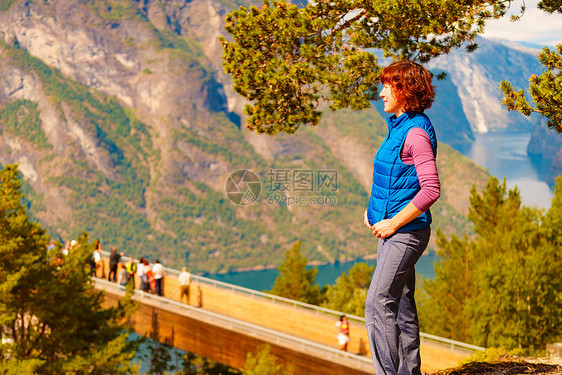 游客妇女越过Stestein瞭望台,看着挪威峡湾山脉的景色徒步旅行,旅途放松旅游景区路线极光游客享受山脉峡湾景图片