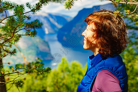 山顶上的游客女人看着挪威峡湾山脉的景色旅游景区路线极光旅行中的假期放松山顶上的游客,挪威图片