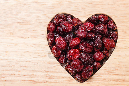 健康高纤维食品,机营养蔓越莓干蔓越莓果木质表背景上呈心形图片
