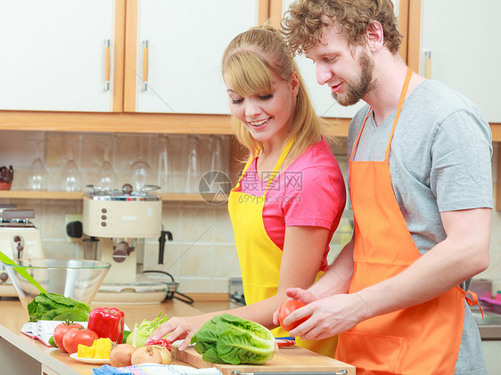 快乐的轻夫妇饭女人男人家里的现代厨房里玩得很开心,同时准备新鲜蔬菜食物沙拉图片