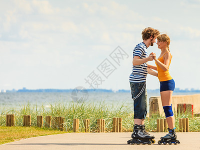 节日,积极的人友谊的轻的穿着溜冰鞋的夫妇骑海边的户外,女人男人长廊上滑行图片