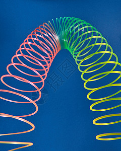 几何形状曲线抛物线由柔彩虹弹簧玩具制成,蓝色背景上以抛物线的形状拉伸细长玩具图片