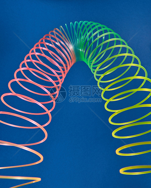 几何形状曲线抛物线由柔彩虹弹簧玩具制成,蓝色背景上以抛物线的形状拉伸细长玩具图片