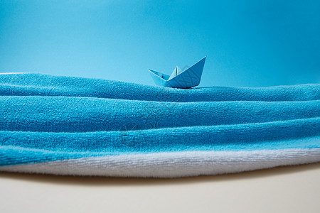 海岸由特里毛巾纸手船制成,蓝天米色沙的背景下,波浪中蓝色的天空米色的沙子,供文字用用沙滩毛巾纸船制成的蓝色大海背景图片