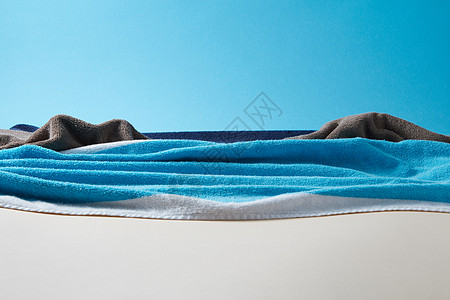 蓝色手工波特里蓝色毛巾双调纸背景的轻天米色沙与海景与岩石制成的蓝色毛巾天空背景图片