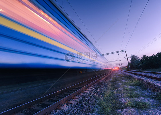夏季夜间铁路上运动的高速客运列车黄昏时移动模糊的现代通勤列车工业景观与火车站紫色的天空运输旅行夜间铁路图片