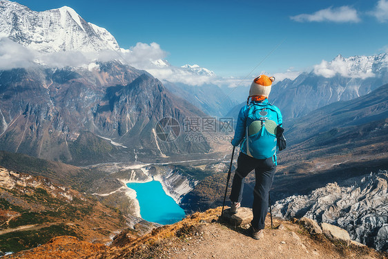 站着的女人背着背包山峰上美丽的山云中,湖日落时蔚蓝的水风景与孤独的女孩,雪岩,天空,冰川尼泊尔旅行徒步图片