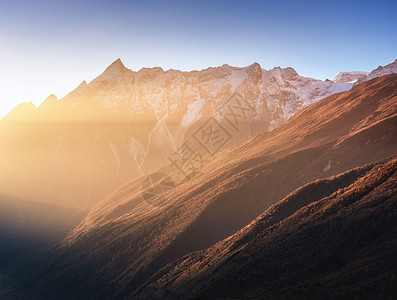 美丽的山脉雪峰阳光明媚的早晨尼泊尔日出时喜马拉雅山脉的轮廓五颜六色的景观,高岩石,蓝天金色的阳光神奇的喜马拉图片