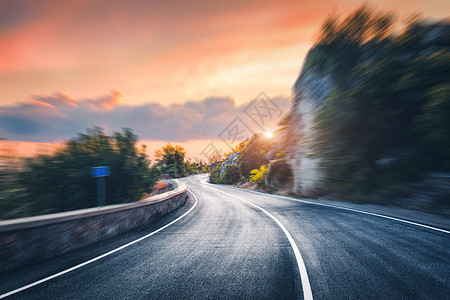日落时的山路运动模糊的效果沥青路模糊的背景与岩石,橙色阳光明媚的天空与云夏天快速驾驶美丽的公路运动中运图片