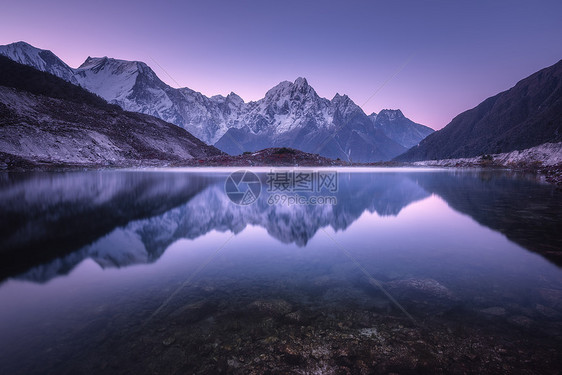 山湖日出时完美的倒影美丽的风景与紫色的天空,雪山,山丘,雾湖黄昏尼泊尔雪覆盖的岩石反射水中图片