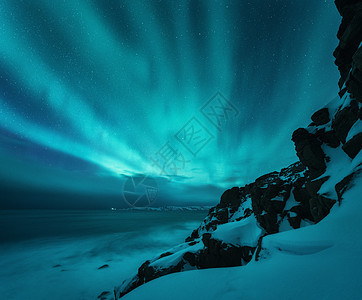 北极光岩石海滩海洋上俄罗斯泰伯卡的北极光极地灯光的星空夜间冬季景观带极光,海水带模糊,雪山旅行图片