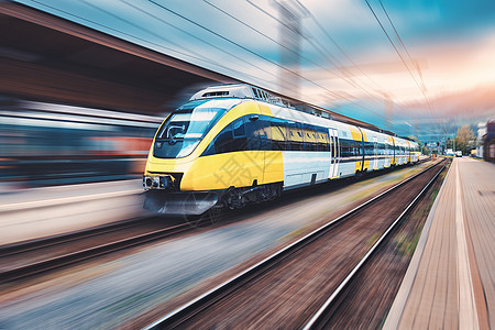 日落时火车站上的高速黄色列车运动现代城际客运列车铁路站台上运动模糊效应工业铁路模糊的背景图片