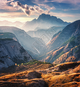 意大利白云石的秋天,明亮的阳光照射下,山上的峡谷被明亮的阳光照亮山岭岩石五颜六色的树木橙色的草高山草地秋天的金背景图片