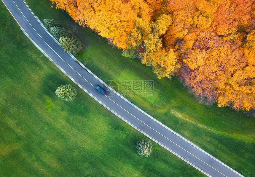 秋天日落时,美丽的绿色田野橙色森林的空中景观美丽的景观与乡村道路,汽车,树木,绿草秋天的高速公路无人机的顶部视图片