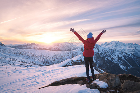 快乐的轻女人雪山日落冬天美丽的苗条女孩山峰上举手臂,雪覆盖着岩石五颜六色的天空白云岩中旅行旅游业图片