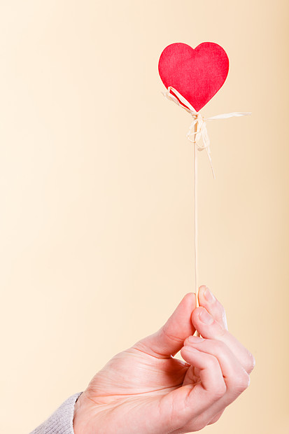 象征爱情浪漫的木棍上的心爱的象征由人的手臂支撑的