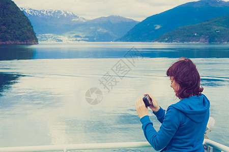 旅游度假旅游游轮上的旅游妇女享受峡湾景观,用相机拍照挪威斯堪的纳维亚欧洲渡船上看的Norddalsfjorde图片