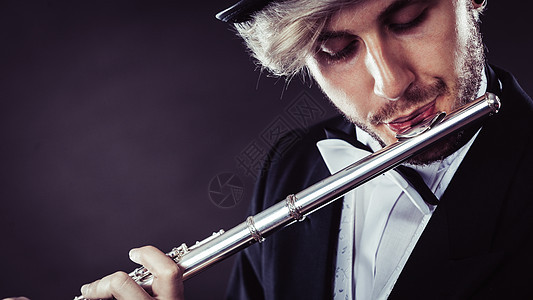 古典音乐,激情爱好穿着优雅的音乐家人长笛工作室拍摄深灰色背景穿着优雅的男音乐家长笛图片