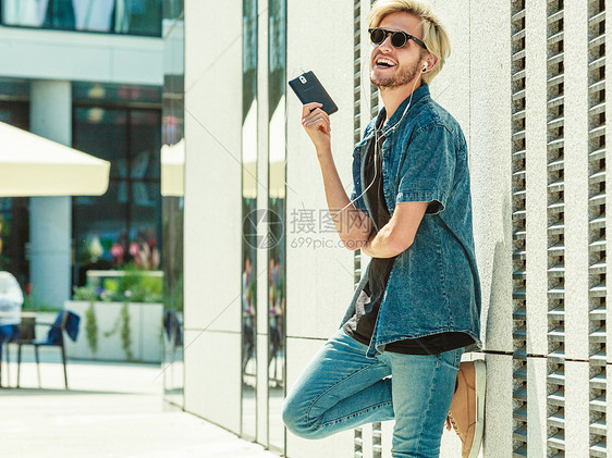 时尚男士站在街道边带着耳机听音乐图片