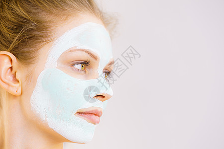 轻的女人脸上戴着白色的绿色泥浆具十几岁的女孩照顾油皮肤,清洁毛孔美容治疗护肤品脸上戴着白色绿色泥浆具的女孩图片