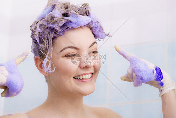 女人戴着乳胶保护手套,同时她的金发上涂上紫色的墨粉洗发水家庭观念中的理发着色女人头发上涂上墨粉洗发水图片