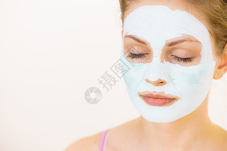 轻的女人脸上戴着绿色的泥浆具,白色的少女照顾油皮肤,净化毛孔美容治疗护肤脸上戴着绿色泥浆具的女孩图片