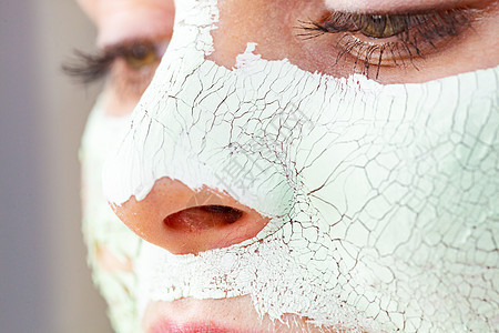 特写女用绿色泥浆具脸上,细节视图十几岁的女孩皮肤上干裂的化妆品美容治疗护肤脸上戴着泥巴具的女孩图片
