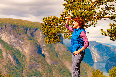 山顶上的游客女人看着挪威峡湾山脉的景色旅游景区路线极光旅行中的假期放松山顶上的游客,挪威图片