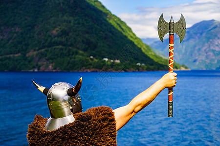 挪威峡湾岸边戴着头盔斧头的维京战士旅游旅游挪威峡湾海岸的维京战士图片