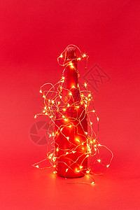 闪亮的诞灯串个创造的彩绘酒瓶上的红色背景与新祝贺卡涂红色酒瓶的诞花环上灯图片