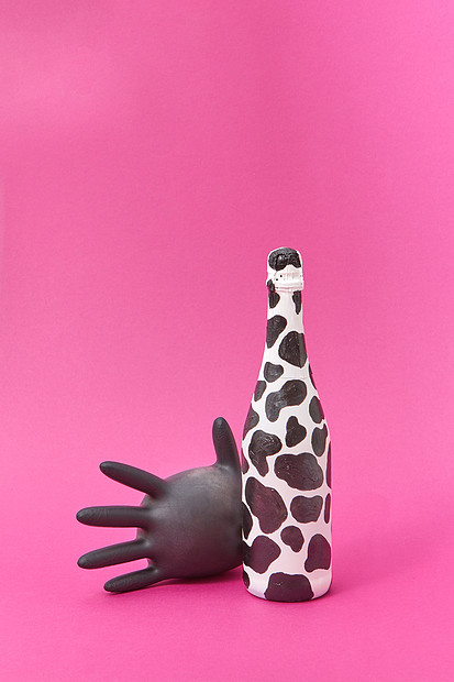 香槟瓶涂白色黑色的斑点黑色气球橡胶手套热粉红色背景上乳胶手套气球