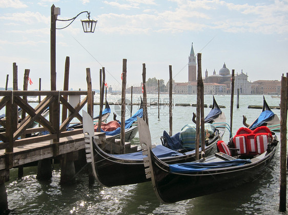 意大利传统船只贡多拉停旧木墩附近,意大利威尼斯乔治马吉奥教堂的背景下传统的意大利贡多拉停泊位附近图片