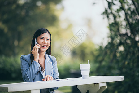 亚洲商界女正用智能手机联系花园里的客户图片