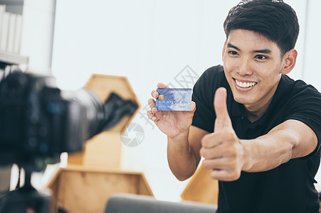 家里的快乐男人摄像机前为Vlog说话轻的亚洲男子博主工作,为互联网录制视频教程图片