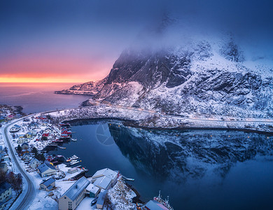 雪山的鸟瞰,海边的村庄,冬天日落时五彩缤纷的天空莱茵河,洛芬岛,挪威的顶级景观穆迪景观与高岩石,房屋,罗布,反射水中图片