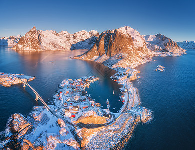 挪威洛福滕岛的小岛桥上的海上雪山的鸟瞰图汉诺伊冬天日出的时候景观与碧水,岩石,建筑物,罗布道路的风景图片