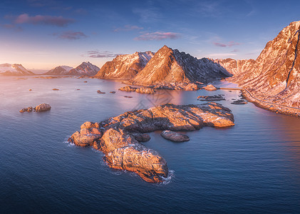 空中俯瞰大海中的岩石,雪山,日落时挪威洛福滕岛旅行冬季景观与小岛屿水,悬崖波浪看图片