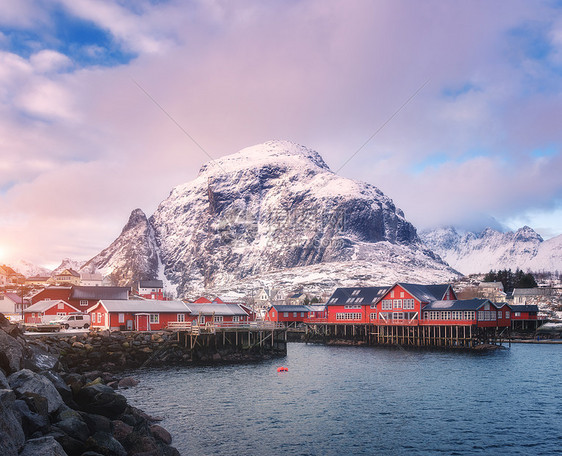 挪威洛福腾群岛的小村庄里,红色的传统RorBuer冬天的日落时风景海,雪山,房子,蓝天紫色的云美丽的罗布海边图片
