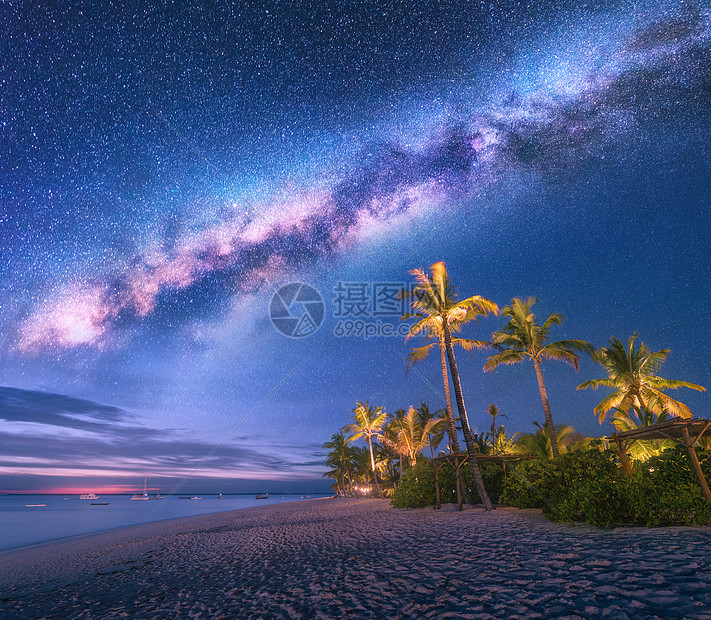 夏天的夜晚,沙滩上棕榈树日光床雨伞的银河海岸景观,美丽的星空,星系绿色的手掌非洲桑给巴尔旅行图片