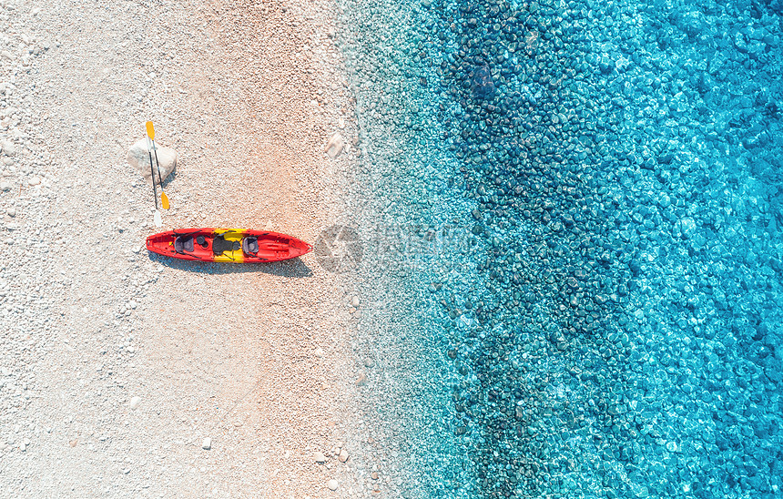空中观看空沙滩与红色独木舟,海岸与透明的蓝色水阳光明媚的日子图片