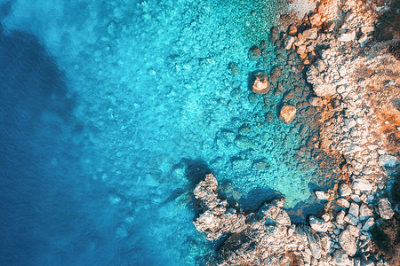 日落时用透明的蓝色水俯瞰岩石海滩海洋夏季日落时亚得里亚海海岸的风景清澈蔚蓝的水石头岩石的景观自然背景图片