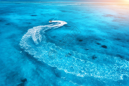 夏季日落时蓝色水中浮水滑板车的鸟瞰图印度洋,桑给巴尔,非洲度假喷气滑雪运动的顶部视图热带海景与移动摩托艇极端背景图片